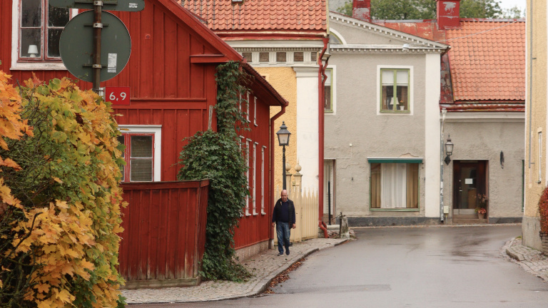 Gata i Vadstena med flera byggnader och promenerande man.